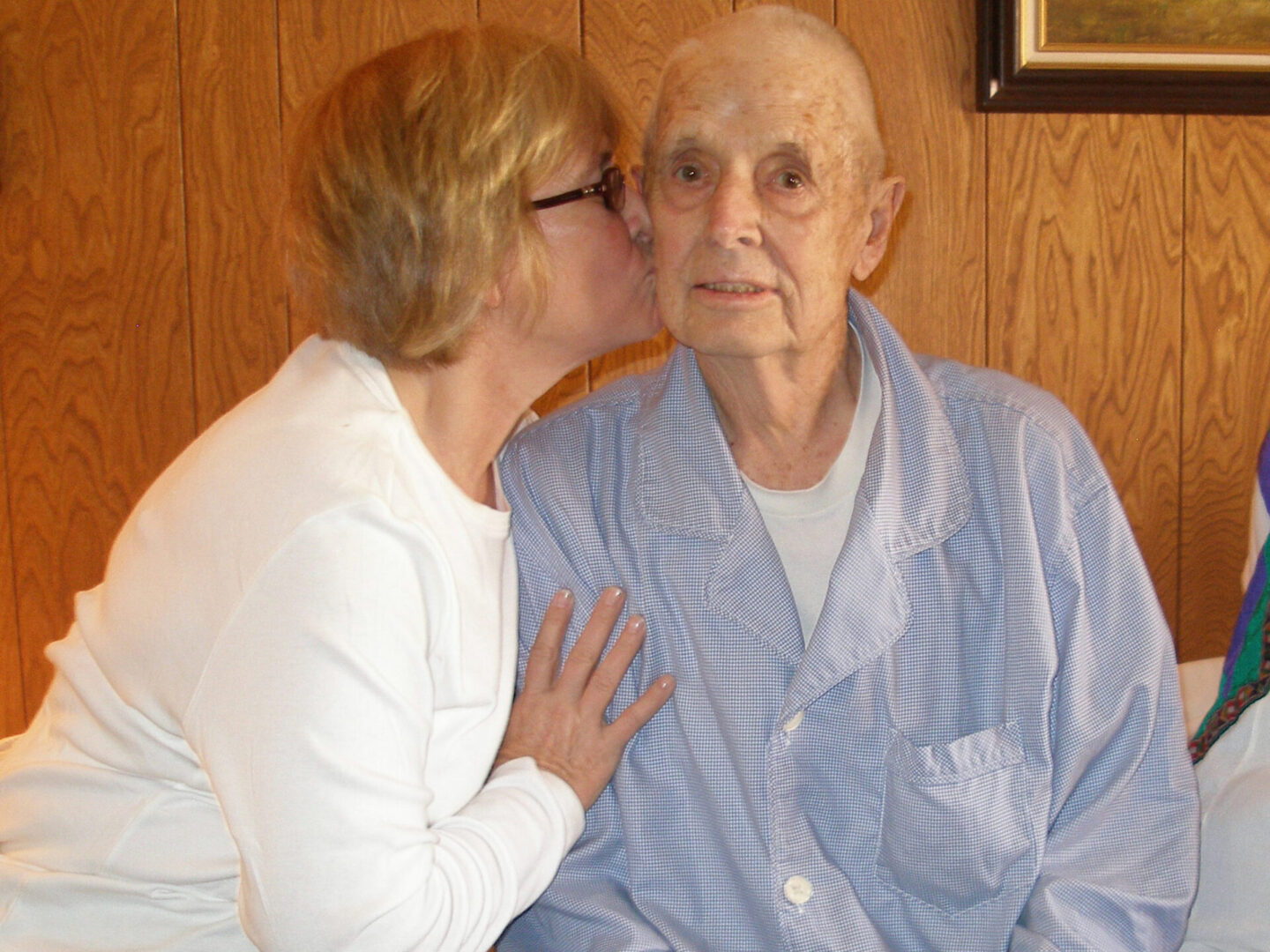 A woman kissing an old man on the cheek.