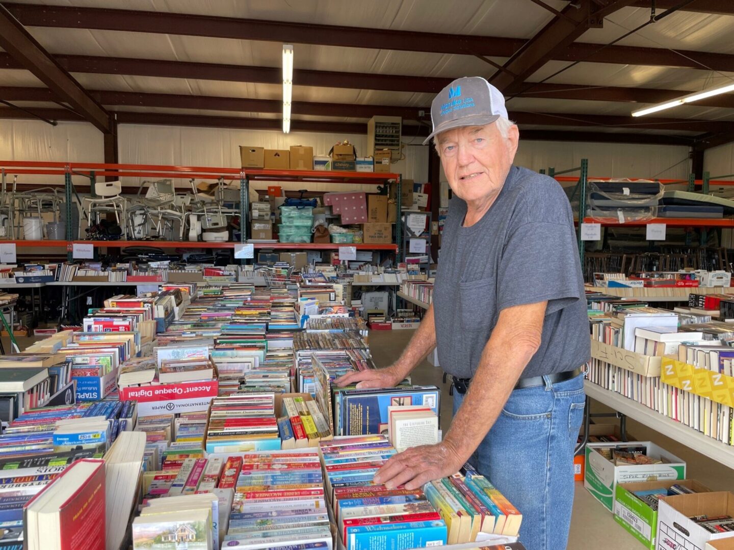 A man standing in front of a large amount of books.