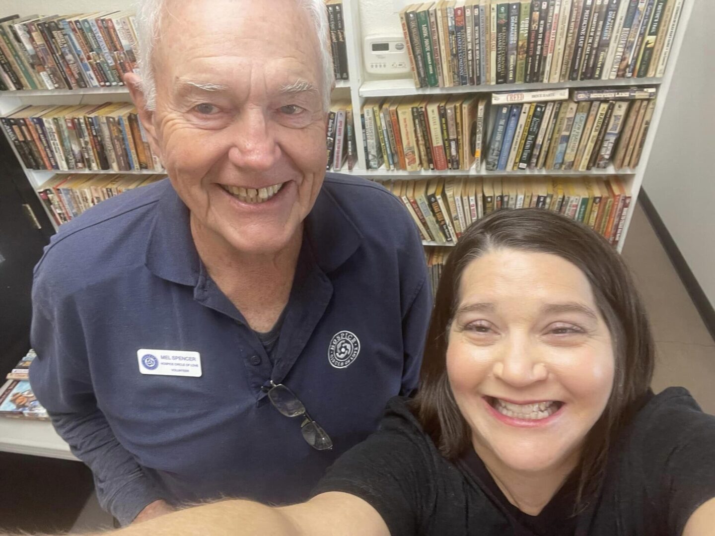 A man and woman smile for the camera in front of shelves.